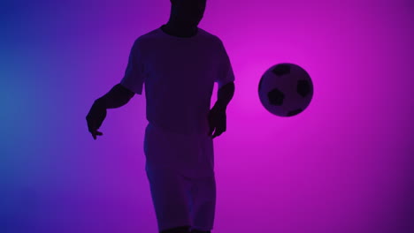Un-Hombre-Negro,-Un-Jugador,-Hace-Malabarismos-Con-Una-Pelota-De-Fútbol-En-Un-Estudio-Oscuro-Con-Luces-De-Neón-En-El-Suelo-Y-Efectos-De-Iluminación-Rojos-Y-Azules-En-Cámara-Lenta.-Futbolista-Profesional-Africano